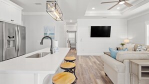A modern kitchen with a central island, stainless steel appliances, and a dining area with stools. - Laguna Haven! 3BR 2BA Sleeps 7! Your Perfect Escape! (Panama City Beach)