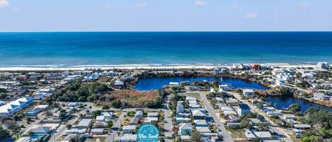 An aerial view of a coastal residential area with a marina, houses, and a beach.