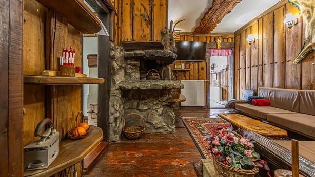 Un interior rústico con chimenea de piedra, paredes de madera, un sofá y una alfombra tejida.