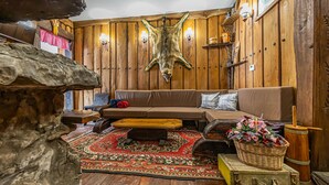 Una habitación acogedora con pared de madera, un sofá de cuero, un tapete estampado y un gran cuero de animal.