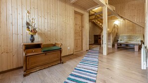 Un interior de madera con un sofá, un banco de madera, una alfombra a rayas coloridas y una escalera que sube a otro nivel.
