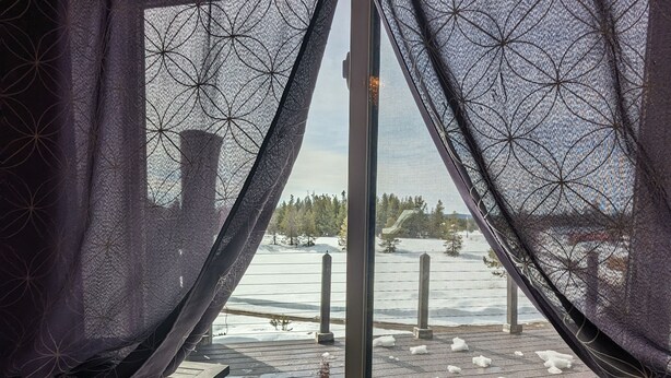 A window with a view of a snowy deck and a forested area. - Cozy cabin loft with a giant soaking tub just 30 minutes from Yellowstone (Island Park)