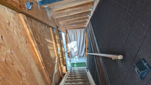 A wooden staircase with a metal handrail, leading to a room with a dark wall and a window. - Cozy cabin loft with a giant soaking tub just 30 minutes from Yellowstone (Island Park)