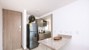 A modern kitchen with a built-in refrigerator, a microwave, and a wooden cabinet. - Urban studio in Laureles with nice view near Unicentro Mall (Medellín)