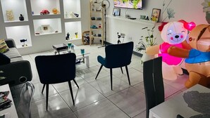 A modern interior with a TV, shelves with various items, and a large teddy bear decoration. - Private Studio, with to much space at the gardens and many amenities like pool. (Toa Alta)