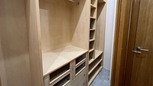 A wooden closet with multiple shelves and drawers, a door, and a tiled floor.