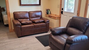 A living room with a brown leather sofa, a recliner, a wooden coffee table, and a framed picture on the wall. - Outdoor Enthusiast's Hideaway and Sauna, Weikert (Millmont)
