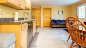 A kitchen with wooden cabinets, a granite countertop, and a sink. There is a wooden dining table with chairs and a bench with a plaid blanket. - Outdoor Enthusiast's Hideaway and Sauna, Weikert (Millmont)