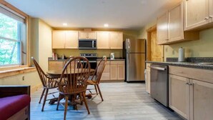 A modern kitchen with wooden cabinets, a dining table with chairs, a refrigerator, and a dishwasher. - Outdoor Enthusiast's Hideaway and Sauna, Weikert (Millmont)