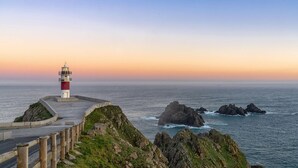 Un phare perché sur une falaise côtière, accessible par une promenade pavée.