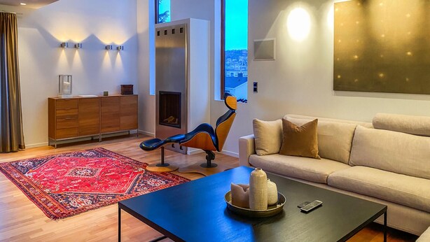 A modern living room with a sofa, a coffee table, a fireplace, and a view of the city through a large window. - Pet friendly home in ålesund (Ålesund)