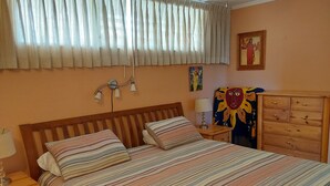 A bedroom with a bed, bedside tables, a lamp, a dresser, and a window with curtains.