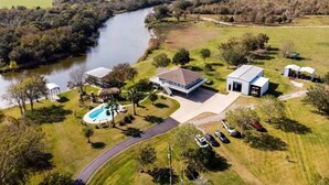 Une grande maison avec une piscine, un court de tennis et une rivière à proximité.