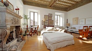 Un dormitorio con una cama grande, chimenea, escritorio y vistas de la ciudad.
