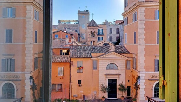 Una calle estrecha con edificios históricos, una torre y una entrada visible a un edificio con un cartel.