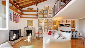 Uma sala de estar ampla com lareira, um sofá branco e escada que leva a um andar superior.