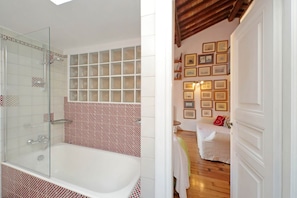 Une salle de bain dotée d’une douche à parois de verre, d’une baignoire et d’un mur recouvert de carreaux formant un motif géométrique.