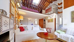 Um quarto espaçoso com uma cama grande, uma mesa redonda e uma varanda com guarda-corpo de metal.