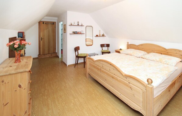 A bedroom with a wooden bed, a desk, a chair, a mirror, and a door. - Ferienhaus in Idylle St. Peter (Aspangberg - St.Peter)
