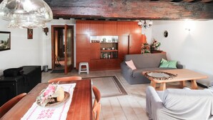 A cozy living room with a wooden dining table, a sofa, and a wooden cabinet. - Ferienhaus in Idylle St. Peter (Aspangberg - St.Peter)