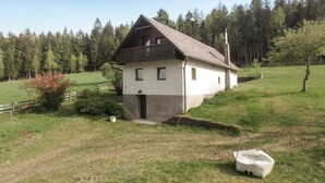 A two-story house with a sloped roof, a balcony on the upper floor, and a stone chimney. - Ferienhaus in Idylle St. Peter (Aspangberg - St.Peter)