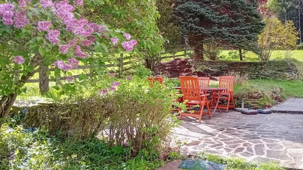 A garden patio with stone flooring and red chairs. - Ferienhaus in Idylle St. Peter (Aspangberg - St.Peter)