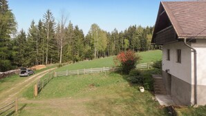 A rural house with a sloped roof, surrounded by a fenced yard and a forested area. - Ferienhaus in Idylle St. Peter (Aspangberg - St.Peter)