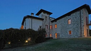 A stone building with multiple windows and a door, surrounded by a well-maintained lawn.
