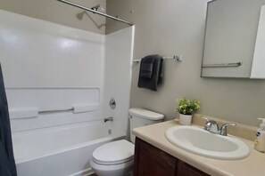 A bathroom with a bathtub, toilet, sink, and a mirror. - ENTIRE HOME | 4BR | Work Ready (4 Desks) | Near Randolph AFB (Converse)