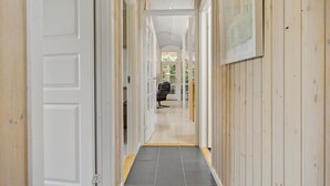 A long, narrow hallway with wooden paneling on the walls and a tiled floor.