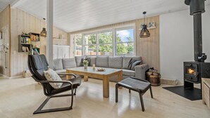 A cozy living room with a sofa, chairs, a coffee table, and a wood-burning stove.