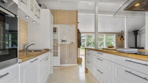 A modern kitchen with white cabinetry, wooden countertops, and a built-in oven.