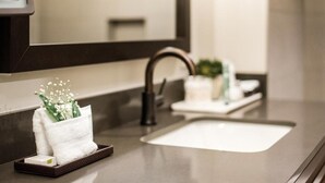 Ein modernes Badezimmer mit einem großen Spiegel, einem Waschbecken und einem Handtuchhalter mit einer Zierpflanze.