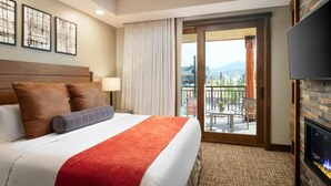 Ein Hotelzimmer mit Bett, Fernseher, Kamin und einem Balkon mit Blick.