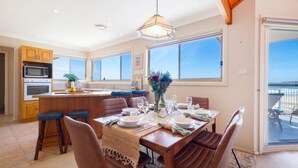A spacious kitchen with a central island, large windows, and a view of the sea. - Dellwood – absolute beachfront on Jones Beach (Kiama Downs)