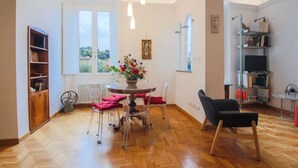 A dining area with a round table, chairs, a radiator, and a bookshelf.