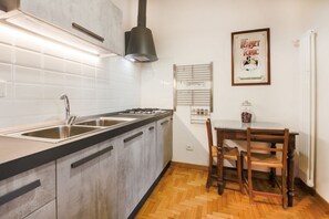 Uma cozinha com pia dupla, fogão a gás e mesa de jantar de madeira com cadeiras.