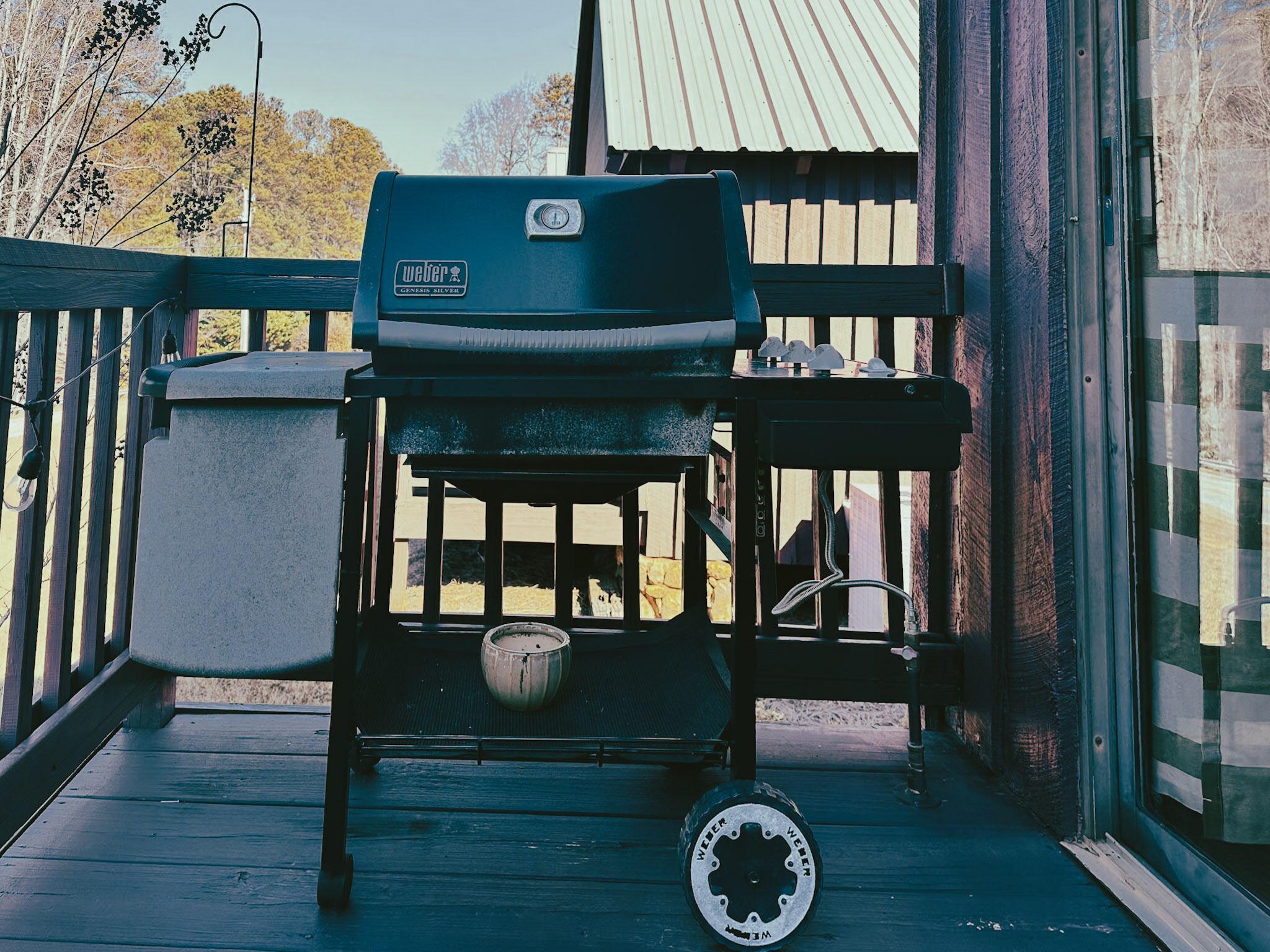 En Weber Genesis Silver grill på en træterrasse med en metal gryde og et grydelåg.
