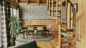 Un intérieur en bois comprenant un coin repas, un escalier et de grandes fenêtres.