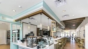 Una cuina moderna amb una illa central, il·luminació penjant i una zona de bar amb tamborets.