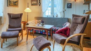 Kodikas olohuone, jossa on sohva, kaksi nojatuolia, sohvapöytä ja lamppu.