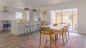 Cozinha moderna com ilha central, banquetas e mesa de jantar com cadeiras.