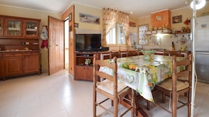 A cozy kitchen with wooden cabinets, a dining table with chairs, a television, and a refrigerator. - 2 bedroom awesome home in Altavilla Milicia (Altavilla Milicia)