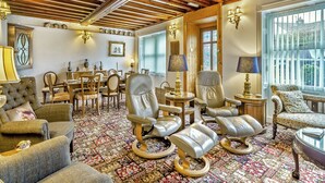 A spacious room with a high wooden ceiling, leather chairs, a patterned carpet, and a dining area with wooden furniture. - 4 bedroom accommodation in Hawes (Hawes)