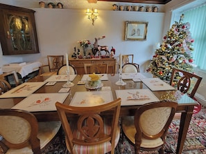 Een eetkamer met een kerstboom, houten meubels en een kroonluchter.