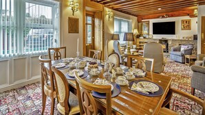 A dining area with a wooden table set for a meal, a fireplace, and a television in the living room. - 4 bedroom accommodation in Hawes (Hawes)
