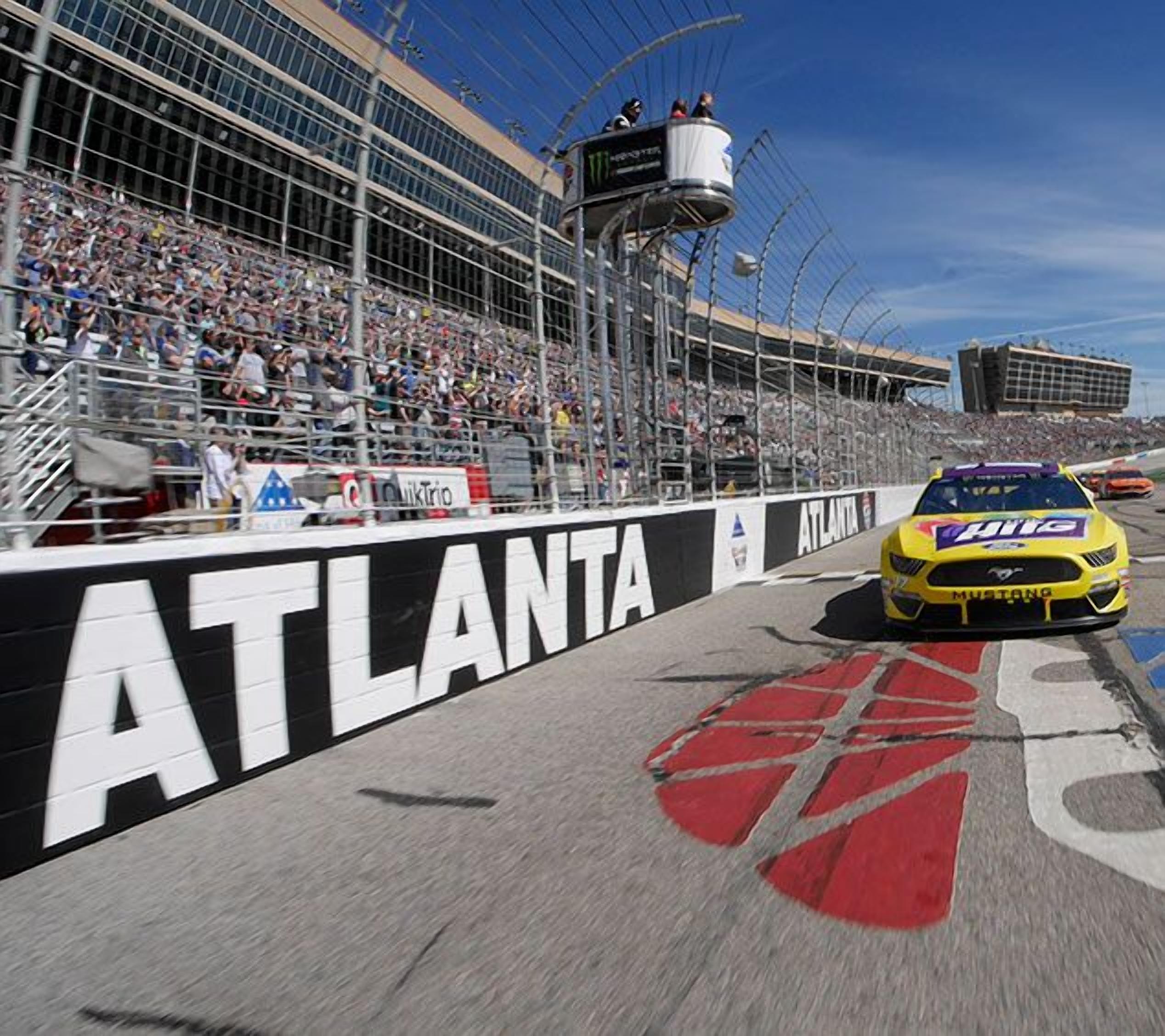 A racing car on a track with a large crowd in the background.