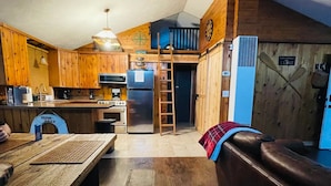 A rustic kitchen with wooden cabinets, a refrigerator, and a ladder leading to a loft bedroom. - Beautiful 2BR+Loft Cottage with amazing views!

 (Beaverton)