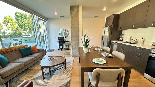 A modern kitchen with dark wooden cabinets, a dining table set for four, and a large window overlooking a patio area. - Like a hotel but better! Pet friendly, exclusive patio, near beach, free parking (San Diego)