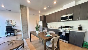 A modern kitchen with dark cabinets, stainless steel appliances, and a dining area with a wooden table and chairs. - Like a hotel but better! Pet friendly, exclusive patio, near beach, free parking (San Diego)
